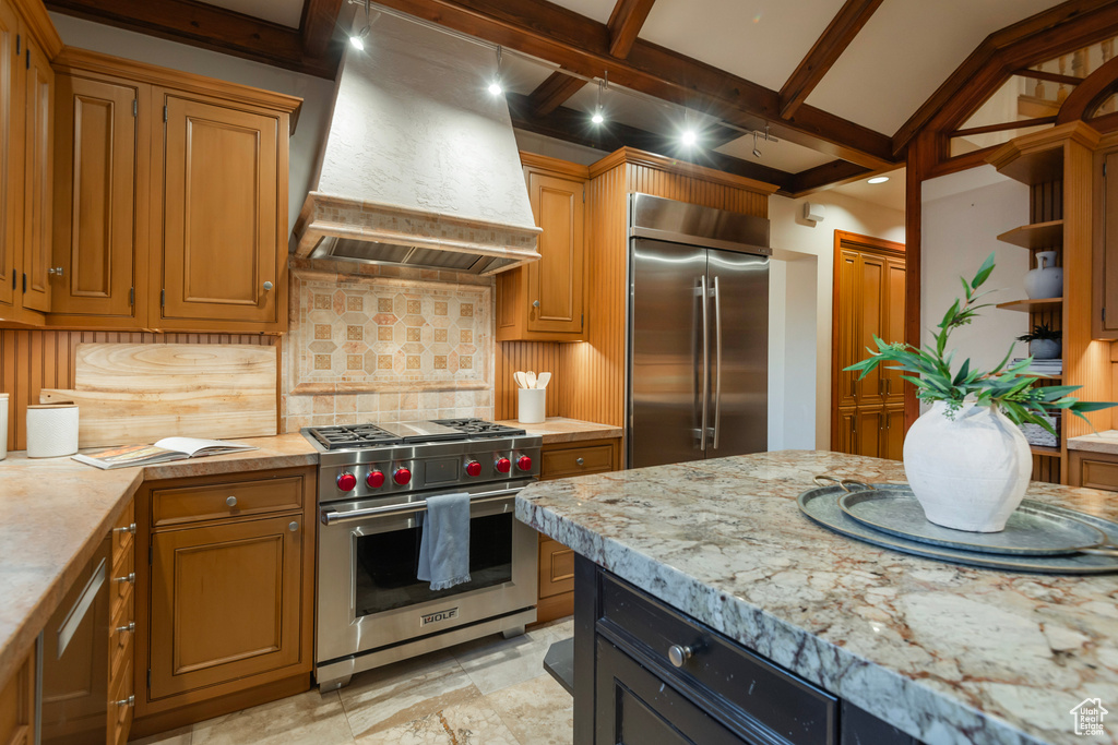 Kitchen with high quality appliances, wall chimney range hood, tasteful backsplash, open shelves, and beamed ceiling