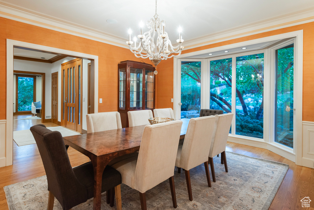 Dining room with ornamental molding, a chandelier, and light wood-style flooring