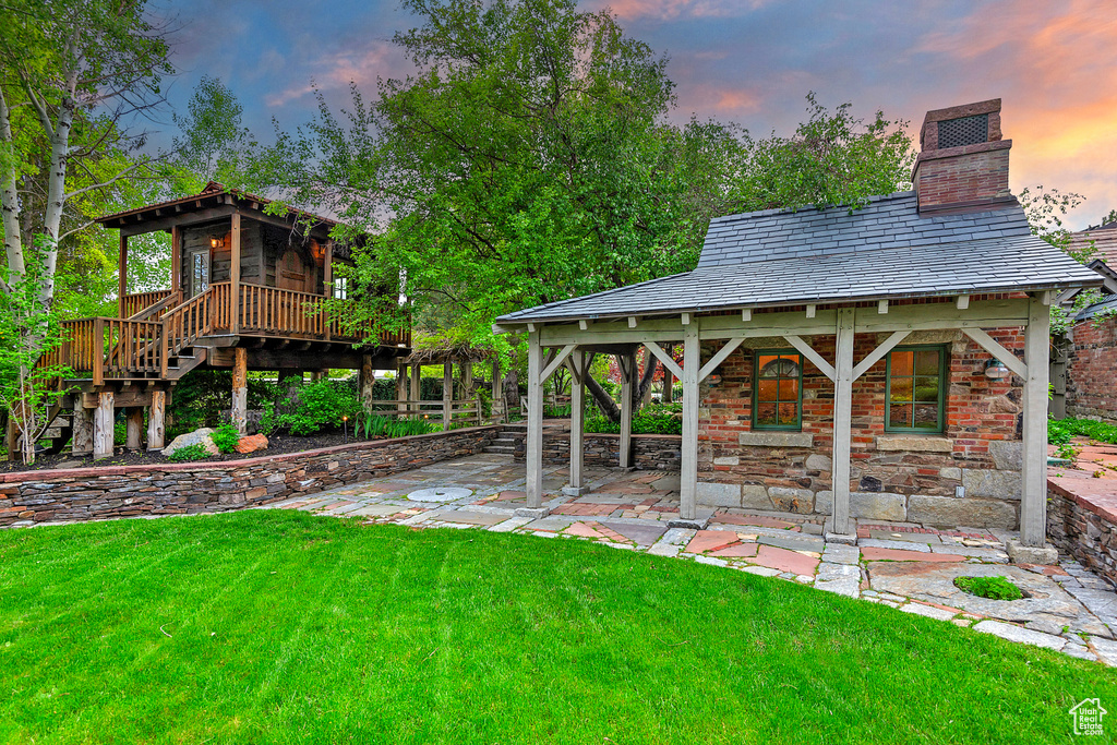 Yard at dusk with a lawn, stairs, and a porch