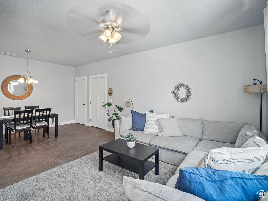 Living room with a chandelier, a ceiling fan, baseboards, and wood finished floors