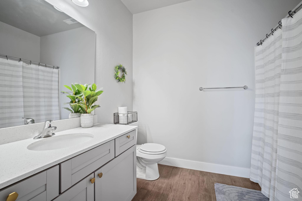 Full bathroom with wood finished floors, vanity, toilet, and baseboards