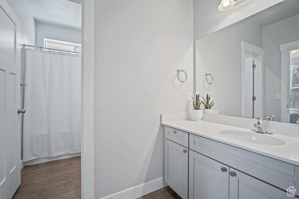 Full bath with vanity, wood finished floors, baseboards, and curtained shower