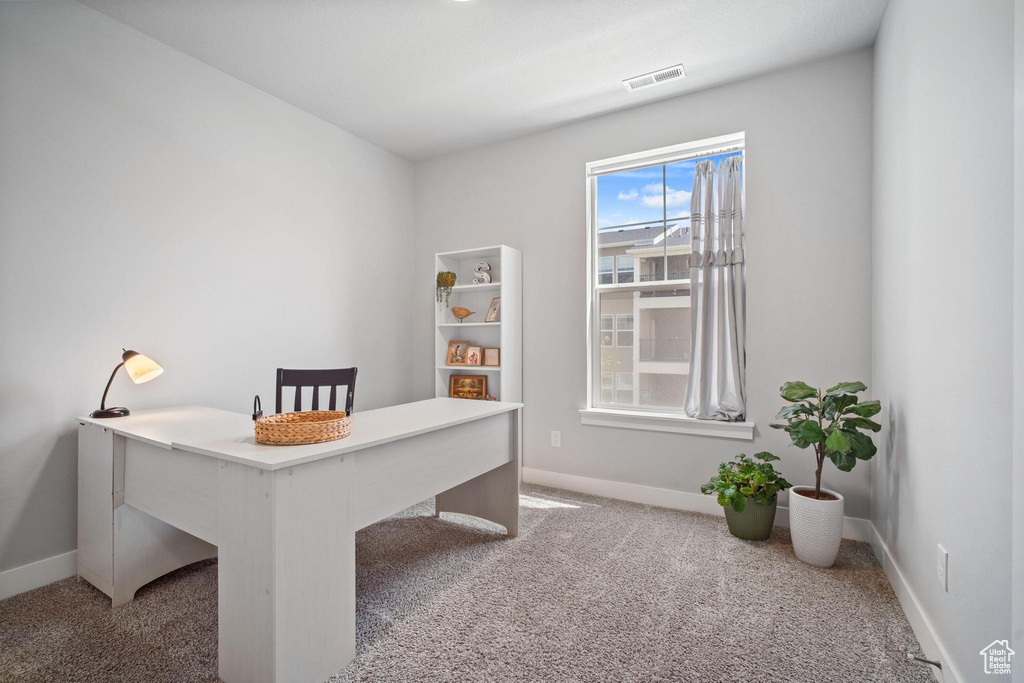 Carpeted home office featuring baseboards