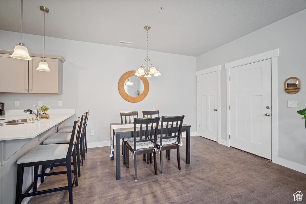 Dining area with dark wood-style flooring, a chandelier, and baseboards