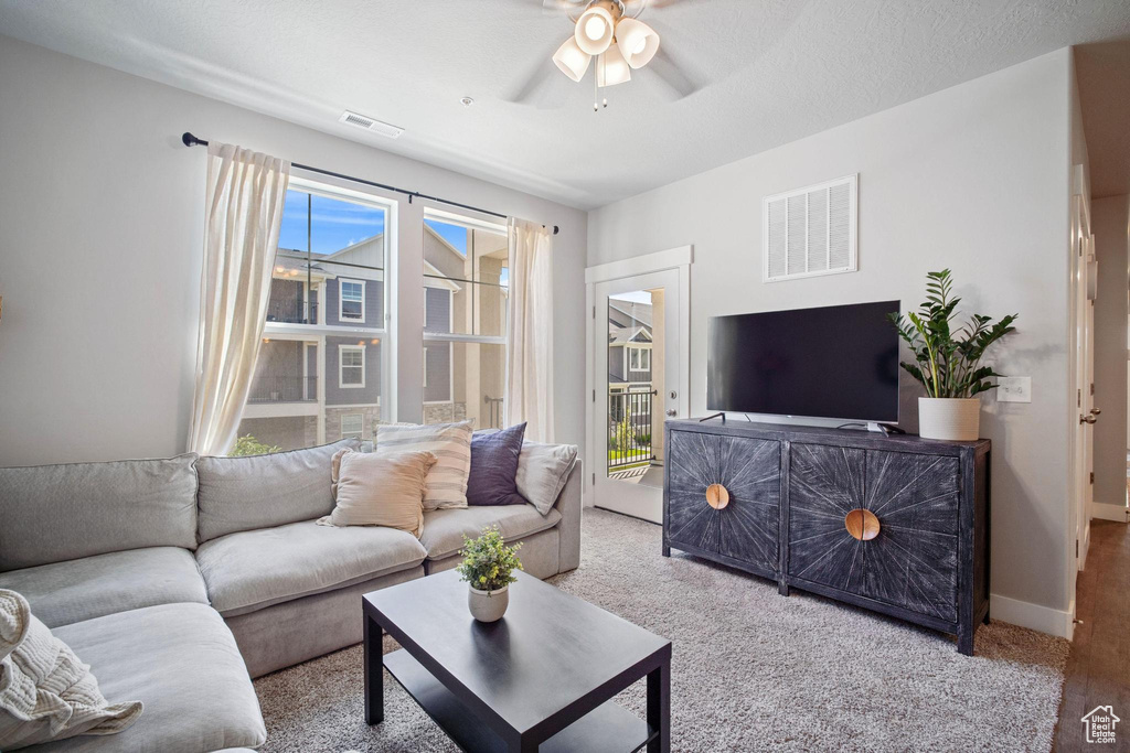 Living room with ceiling fan, baseboards, and carpet floors