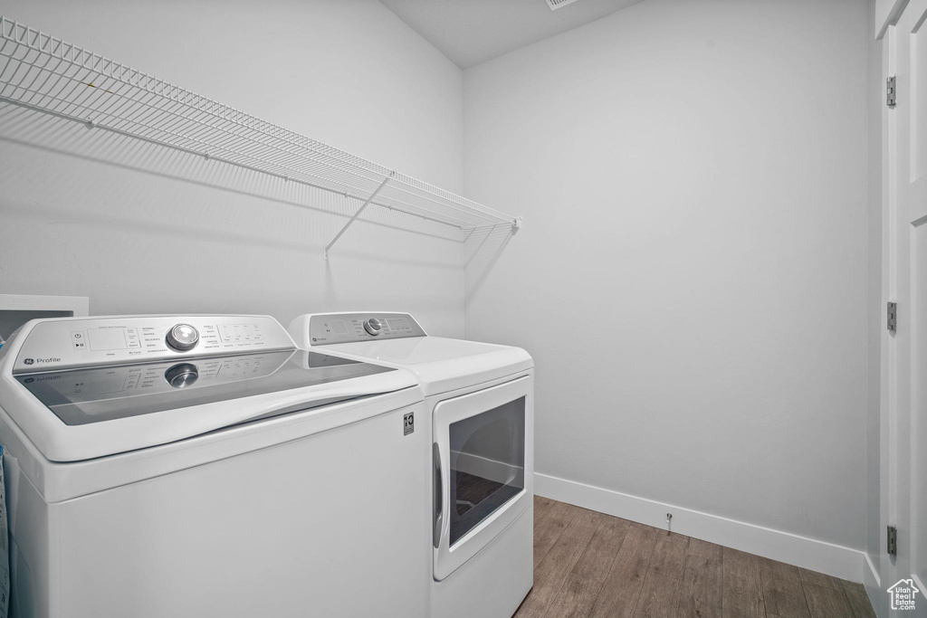 Laundry room with separate washer and dryer, baseboards, and wood finished floors