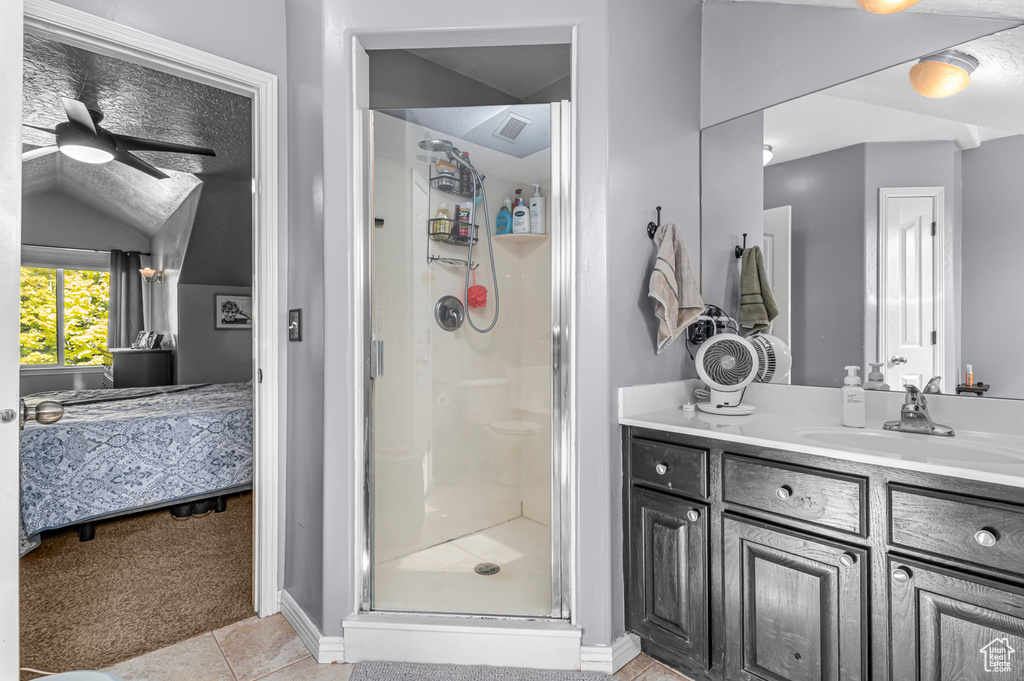 Ensuite bathroom featuring a stall shower, tile patterned floors, vanity, ceiling fan, and baseboards