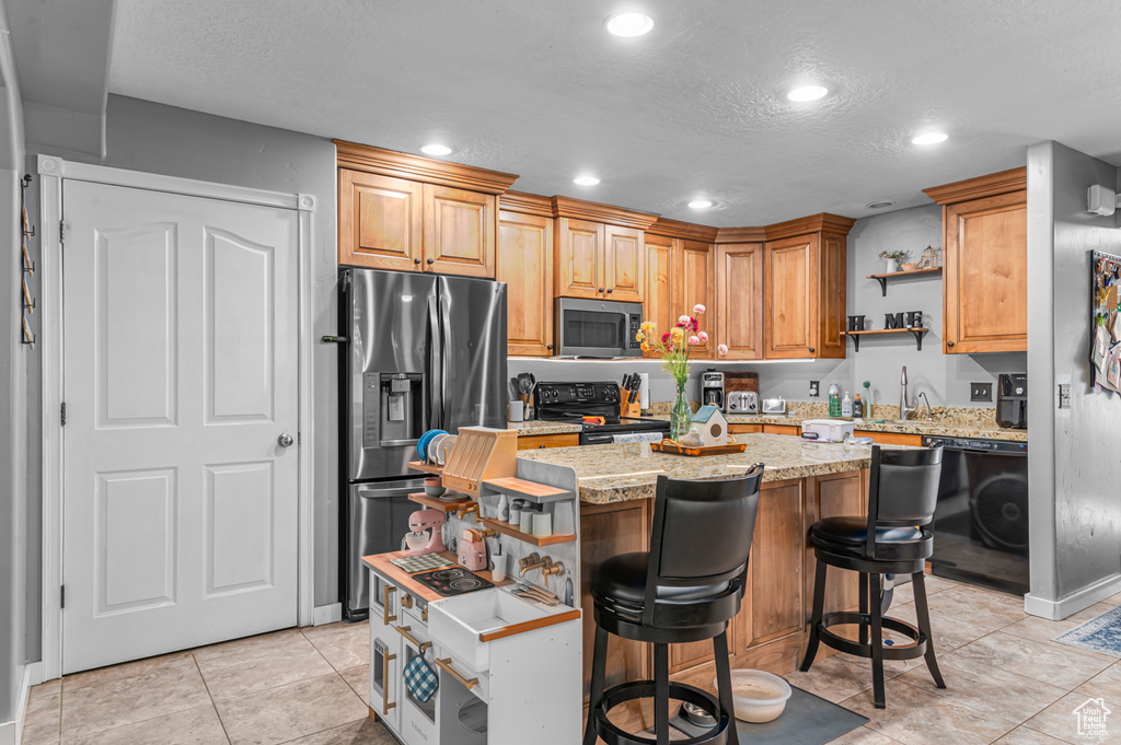 Kitchen with black appliances, recessed lighting, open shelves, a textured ceiling, and a center island