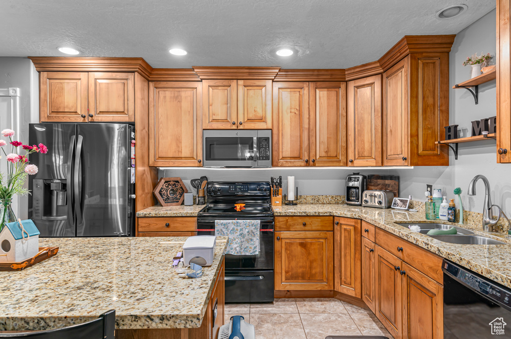 Kitchen featuring black appliances, a sink, open shelves, light stone counters, and recessed lighting
