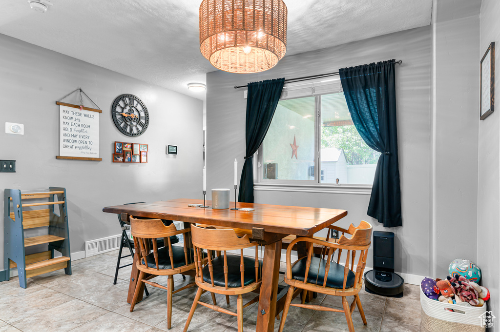 Tiled dining room featuring baseboards and a chandelier