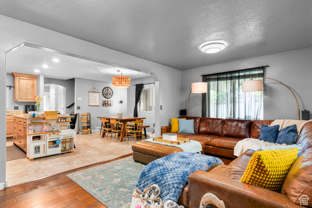 Living room with arched walkways, light wood finished floors, a textured ceiling, and recessed lighting