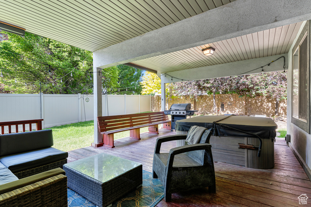 Wooden terrace with a fenced backyard, outdoor lounge area, grilling area, and a hot tub