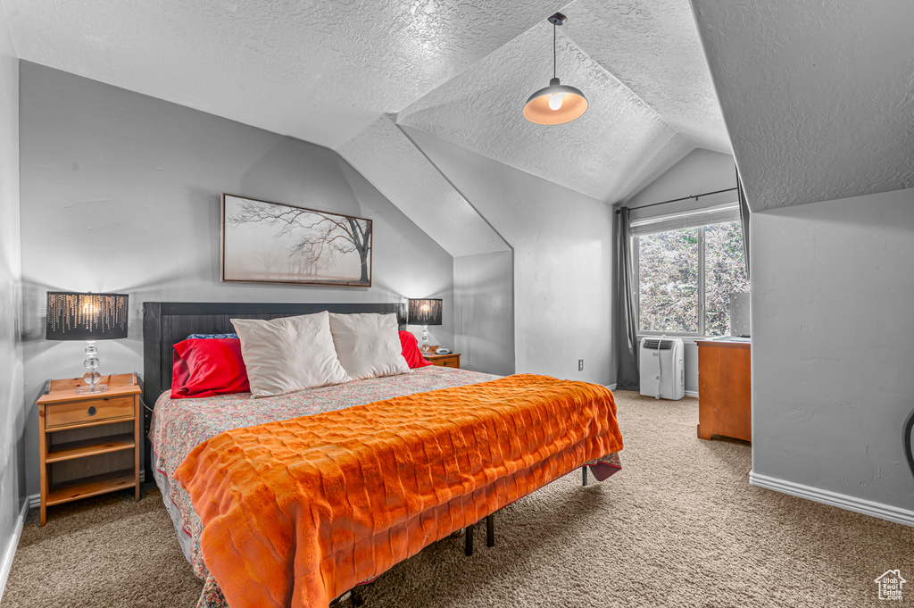 Bedroom with a textured ceiling, carpet floors, vaulted ceiling, and baseboards