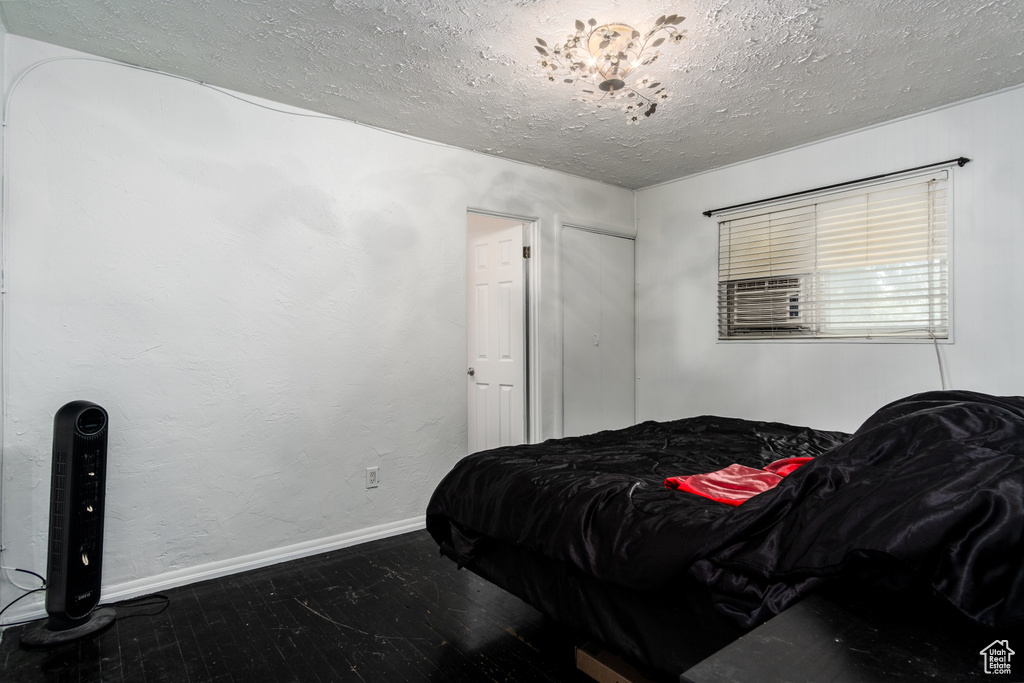 Bedroom featuring a textured ceiling, baseboards, and wood finished floors