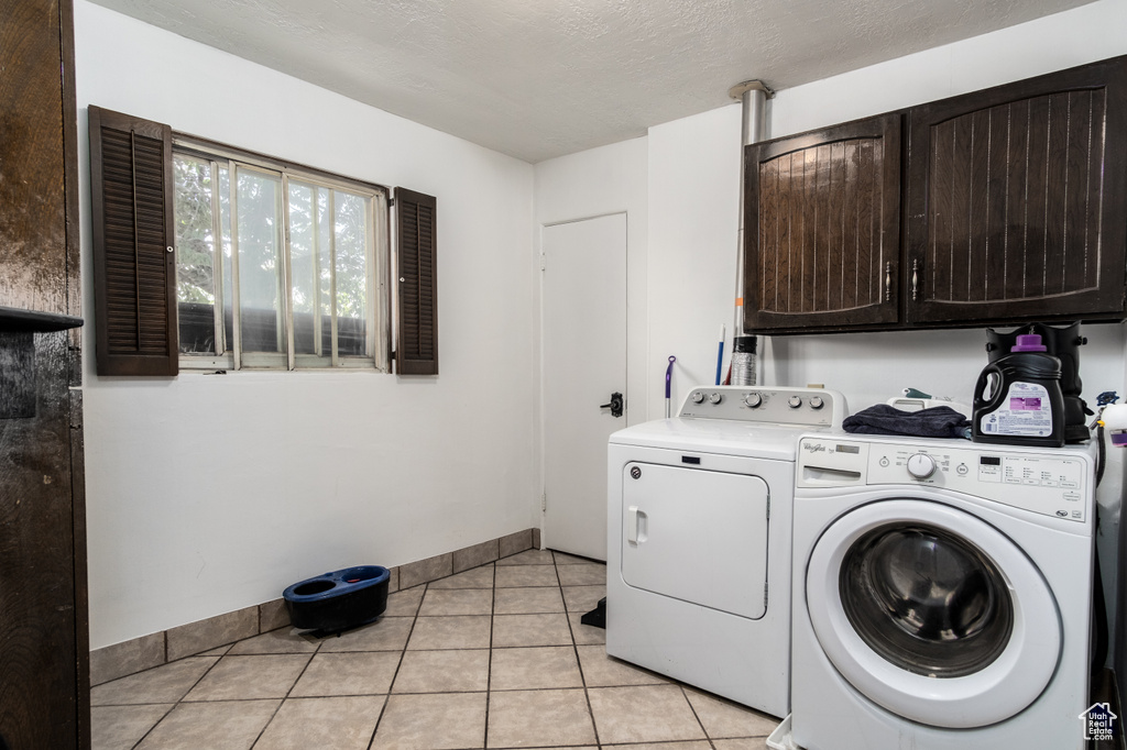 Laundry area with cabinet space, independent washer and dryer, light tile patterned floors, and baseboards