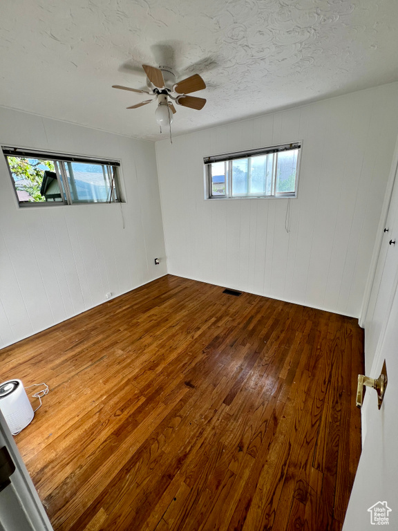 Spare room featuring hardwood / wood-style flooring, a textured ceiling, and a ceiling fan
