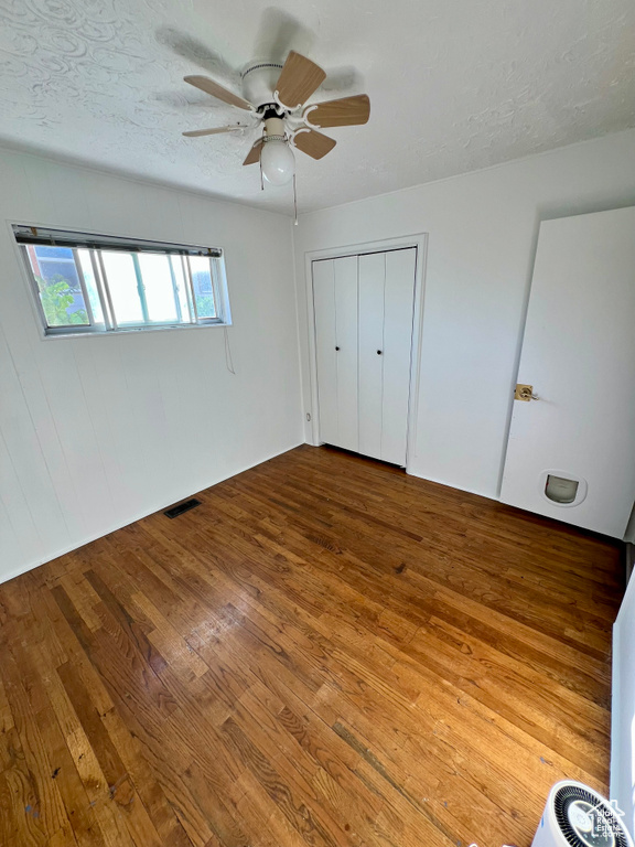 Unfurnished bedroom with hardwood / wood-style floors, a closet, and a ceiling fan