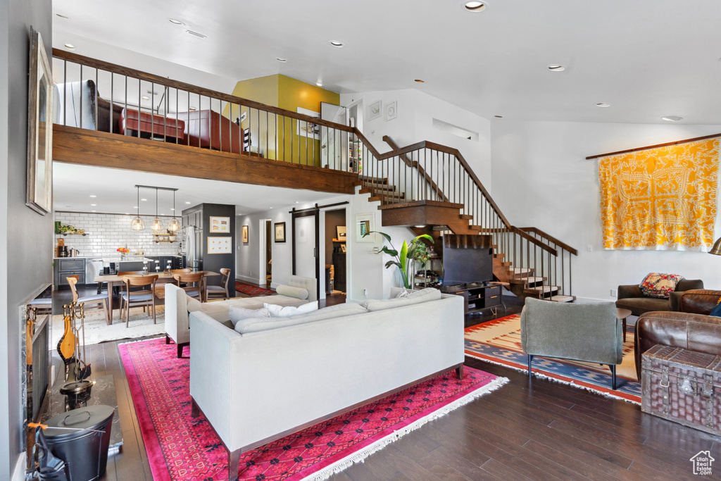 Living room featuring stairway, wood finished floors, a towering ceiling, and recessed lighting