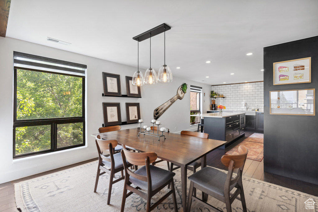 Dining room featuring healthy amount of natural light, light wood-style flooring, recessed lighting, and a chandelier