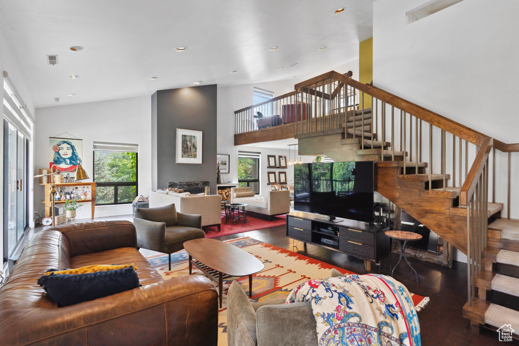 Living area featuring stairs, a towering ceiling, wood finished floors, and recessed lighting