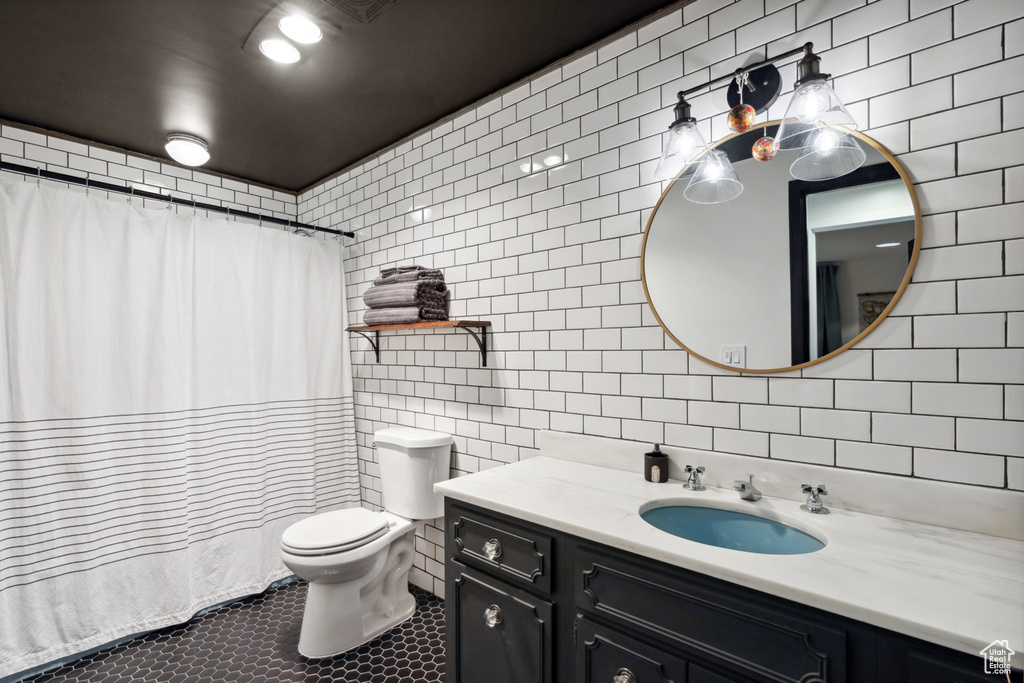 Full bath featuring tile walls, vanity, toilet, tile patterned floors, and curtained shower