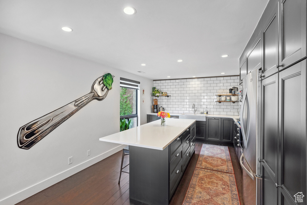 Kitchen with open shelves, a center island, freestanding refrigerator, backsplash, and a breakfast bar area