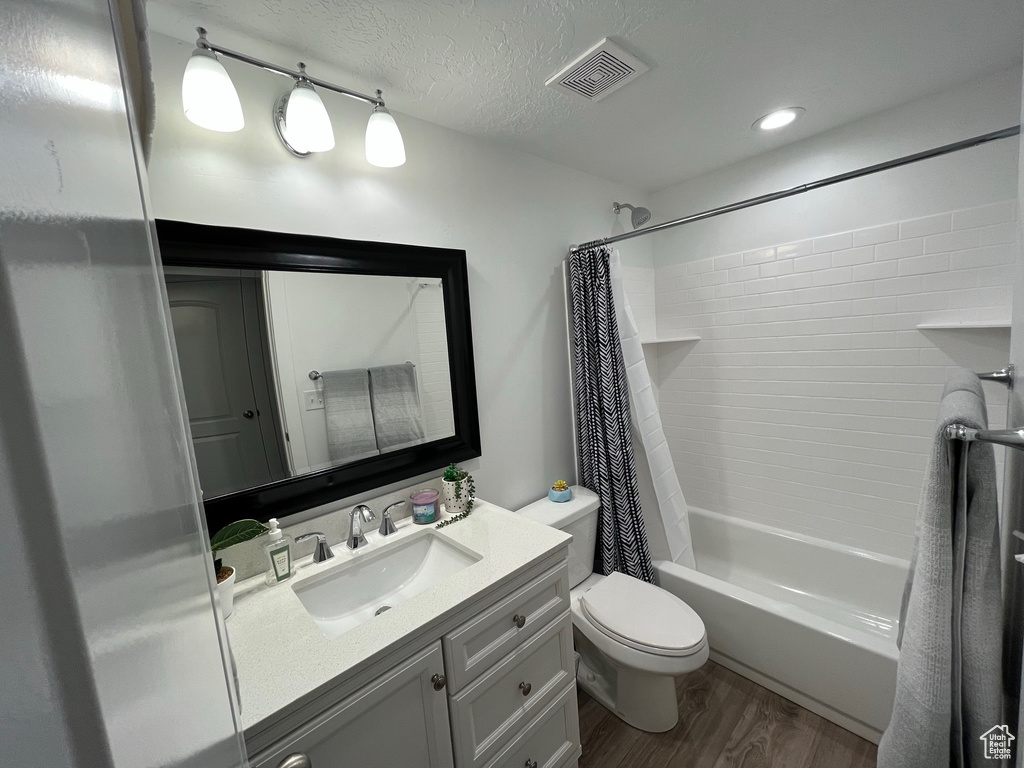 Full bath featuring vanity, toilet, shower / bath combo, and wood finished floors