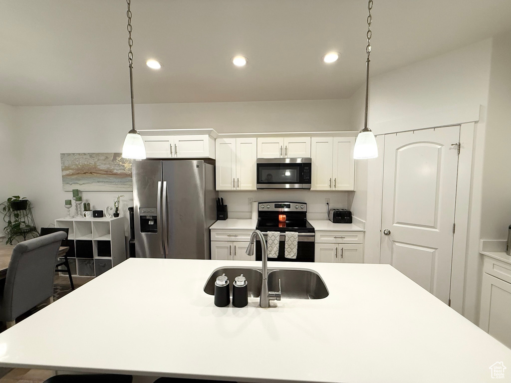 Kitchen with appliances with stainless steel finishes, a sink, light countertops, pendant lighting, and recessed lighting