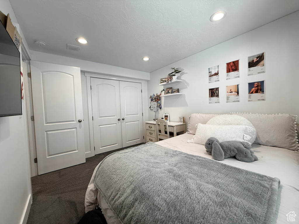 Bedroom with dark colored carpet, recessed lighting, and a closet