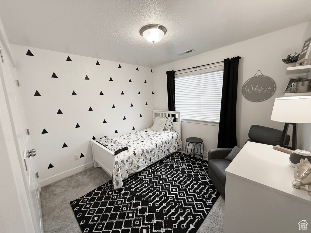 Carpeted bedroom featuring a textured ceiling and baseboards