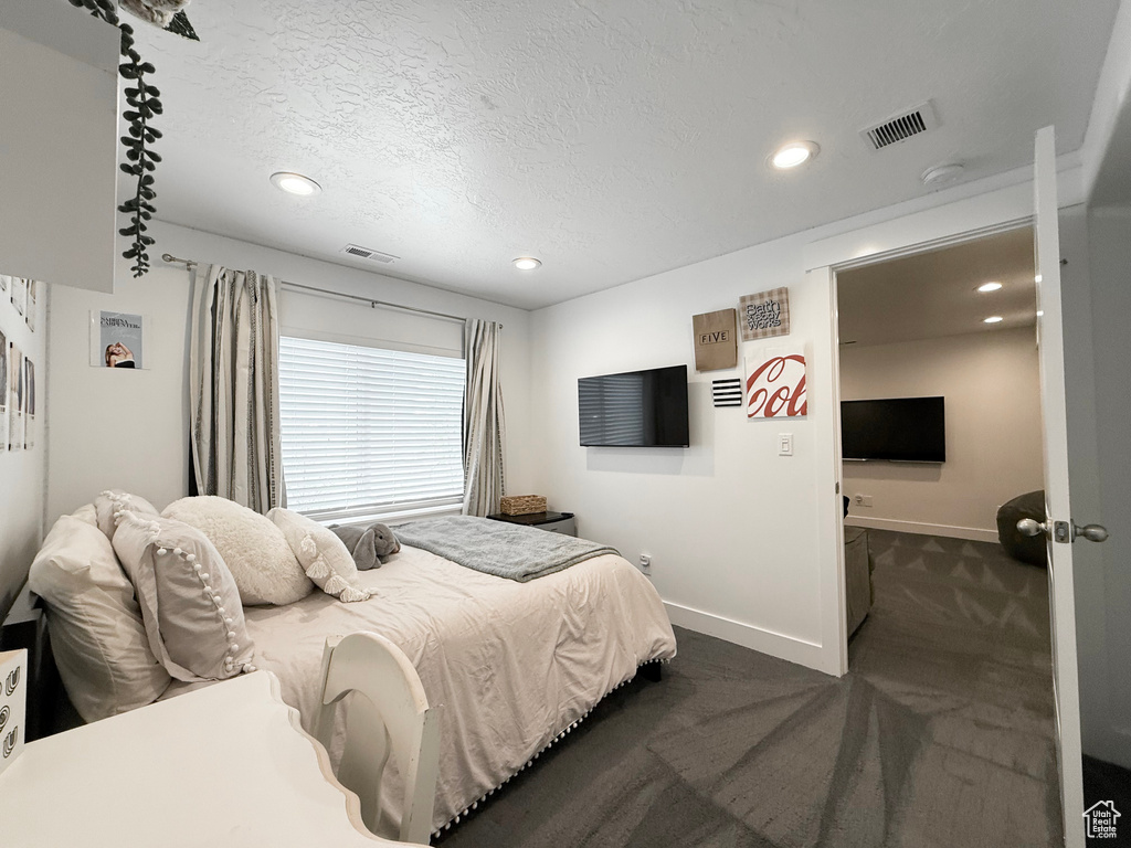 Bedroom featuring dark carpet, baseboards, recessed lighting, and a textured ceiling