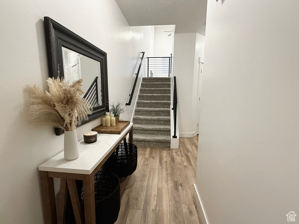 Staircase with wood finished floors, baseboards, and a textured ceiling
