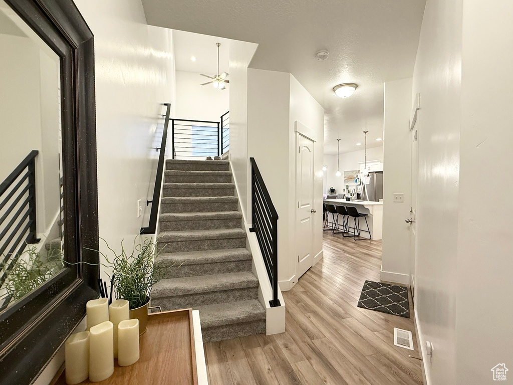Stairway with ceiling fan, wood finished floors, and baseboards