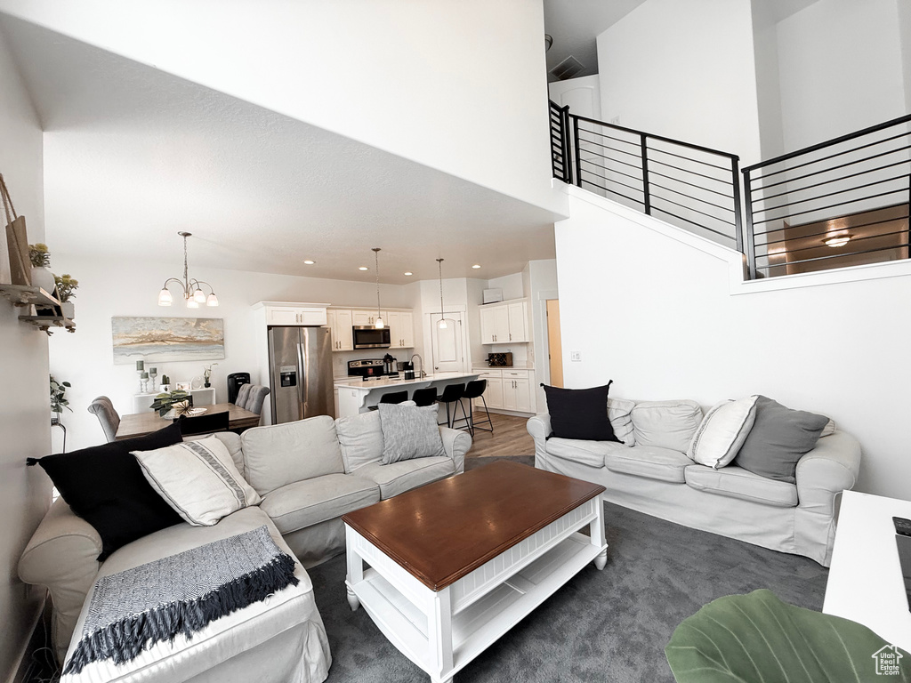 Living area featuring a towering ceiling, stairs, wood finished floors, a chandelier, and recessed lighting