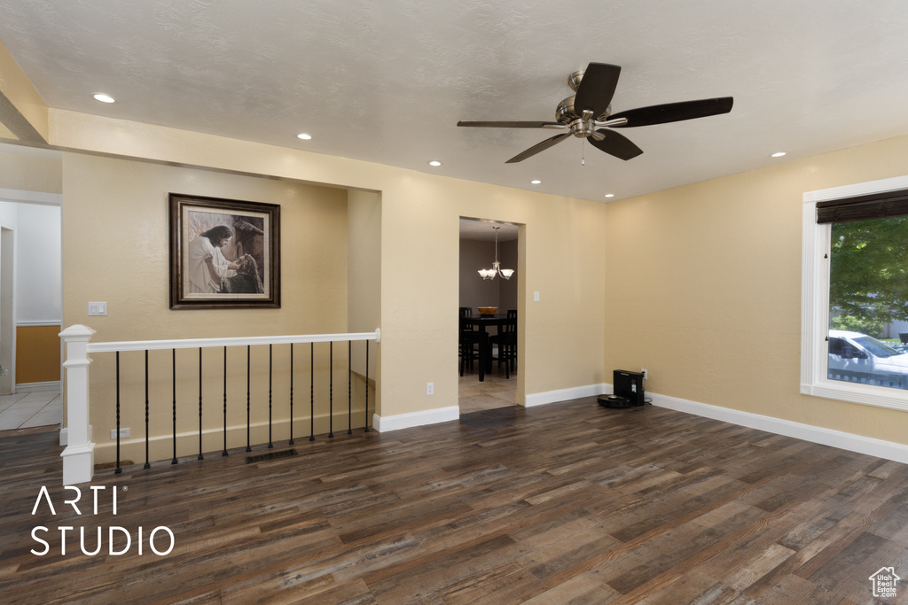 Unfurnished room featuring wood finished floors, a ceiling fan, baseboards, recessed lighting, and a chandelier