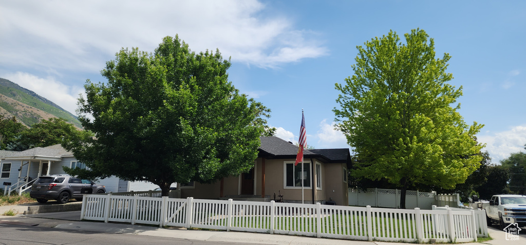 Obstructed view of property with stucco siding, a fenced front yard, and a mountain view