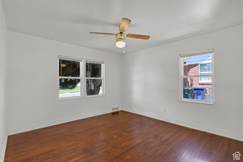 Unfurnished room with dark wood finished floors, baseboards, and a ceiling fan