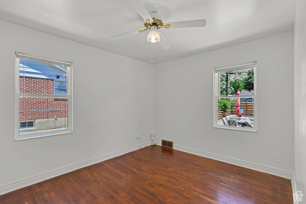 Unfurnished room featuring dark wood finished floors, baseboards, and ceiling fan