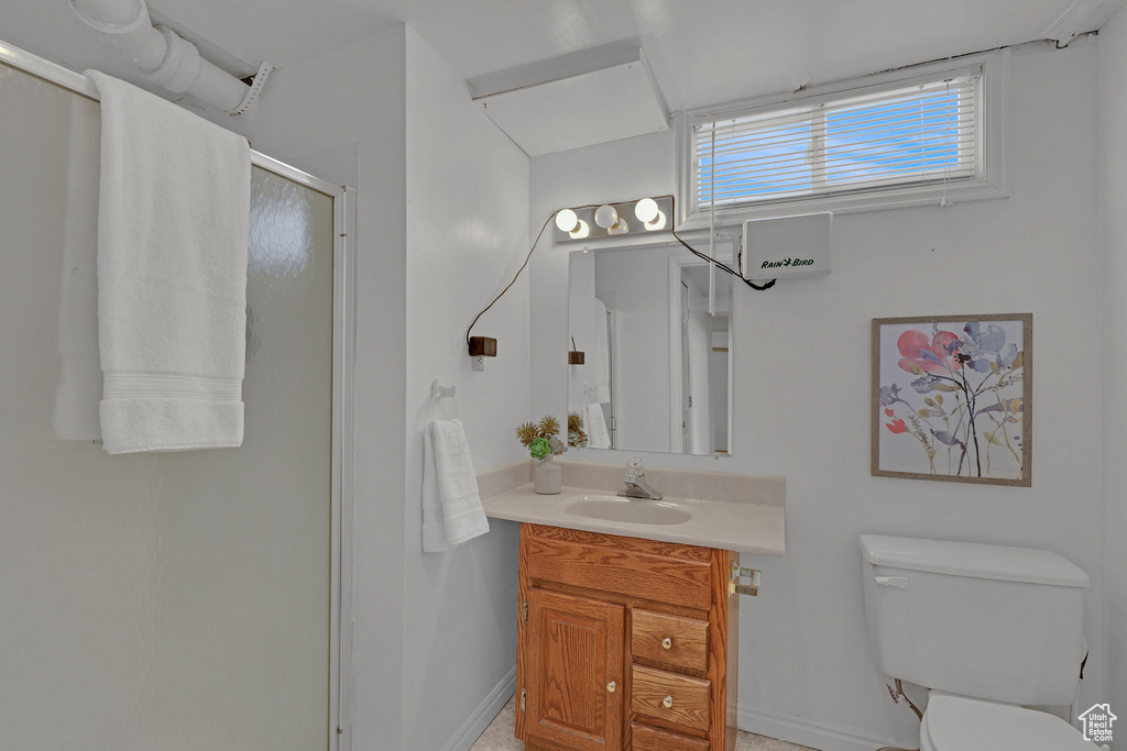 Full bath with a stall shower, vanity, toilet, and baseboards
