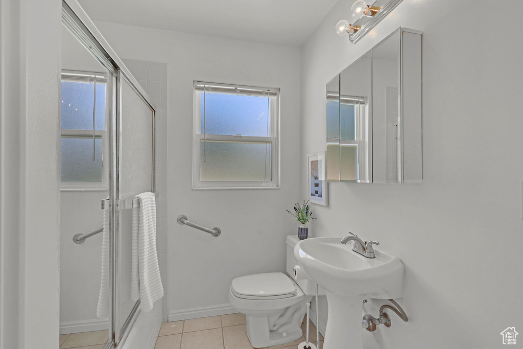 Full bath with a shower with door, tile patterned floors, toilet, baseboards, and a sink