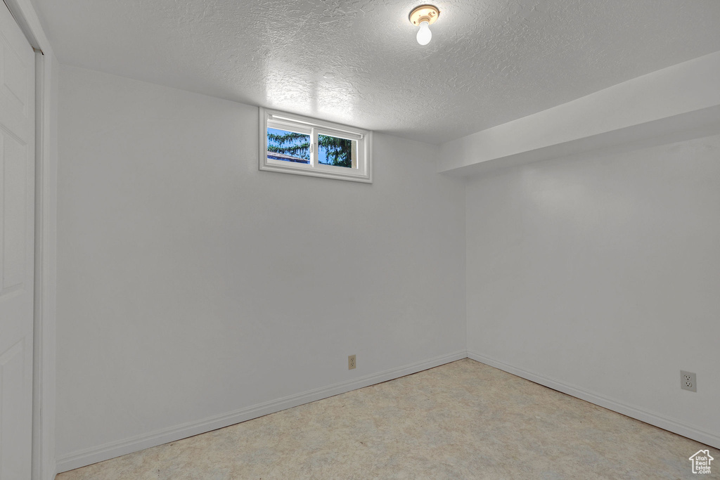 Basement with a textured ceiling, baseboards, and carpet flooring