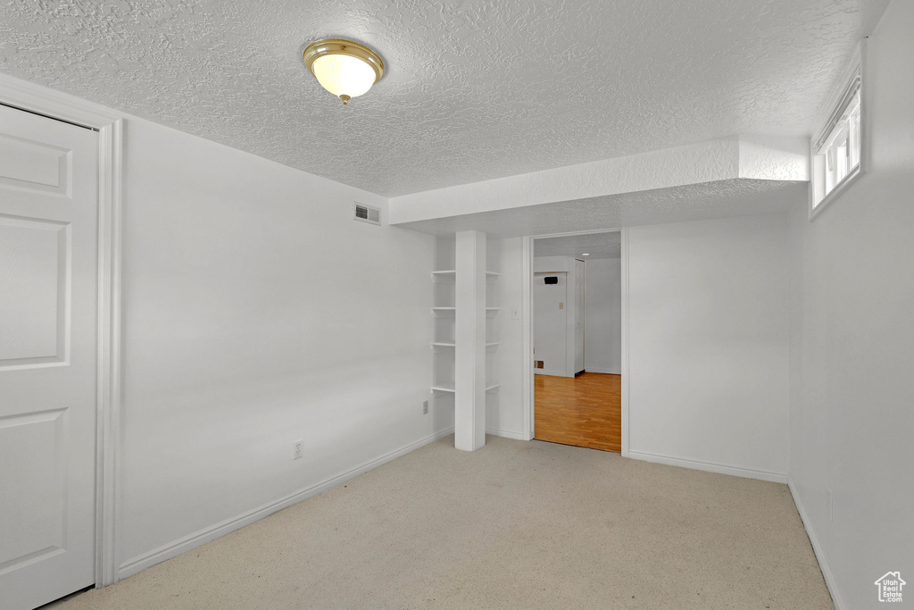 Carpeted empty room with a textured ceiling and baseboards
