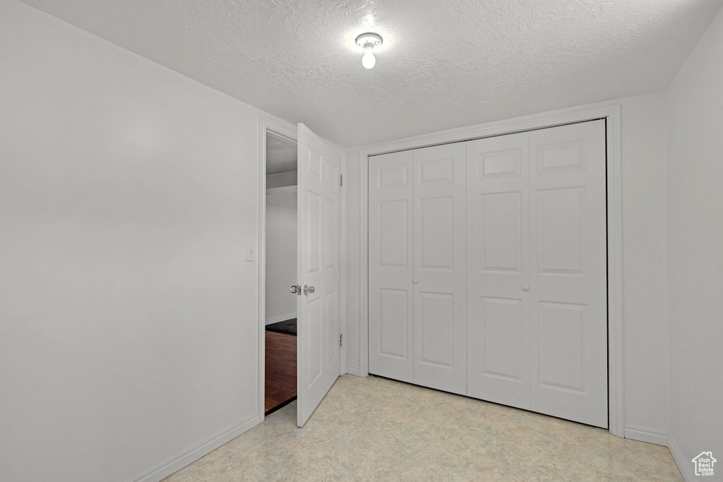 Unfurnished bedroom featuring a textured ceiling, baseboards, and a closet