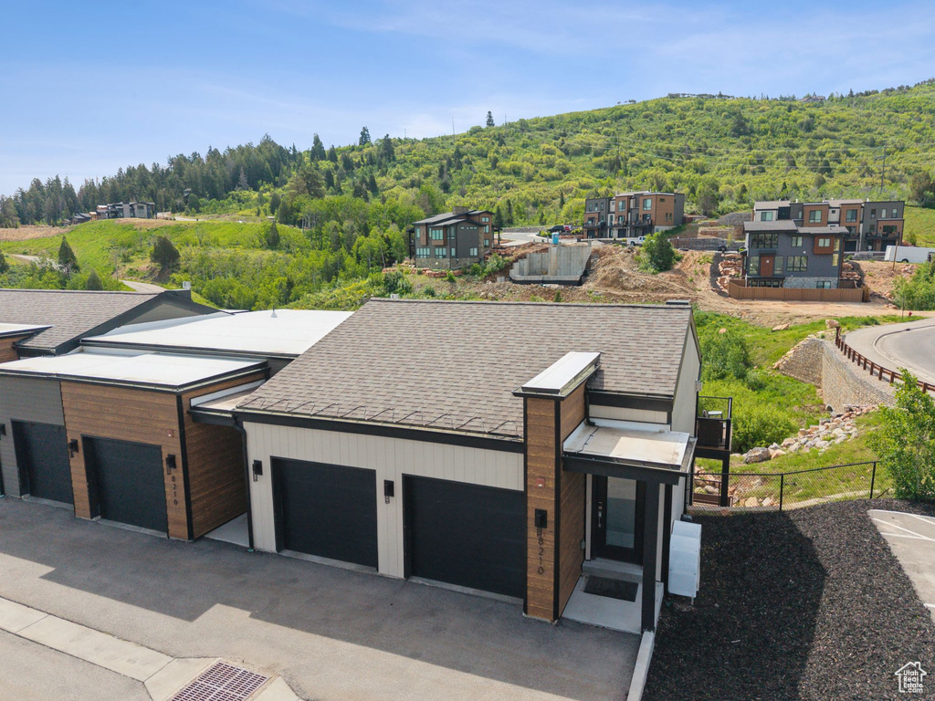 Modern home with a wooded view and roof with shingles