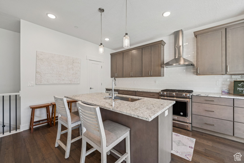 Kitchen with wall chimney range hood, stainless steel gas range, a sink, dark wood-style floors, and recessed lighting