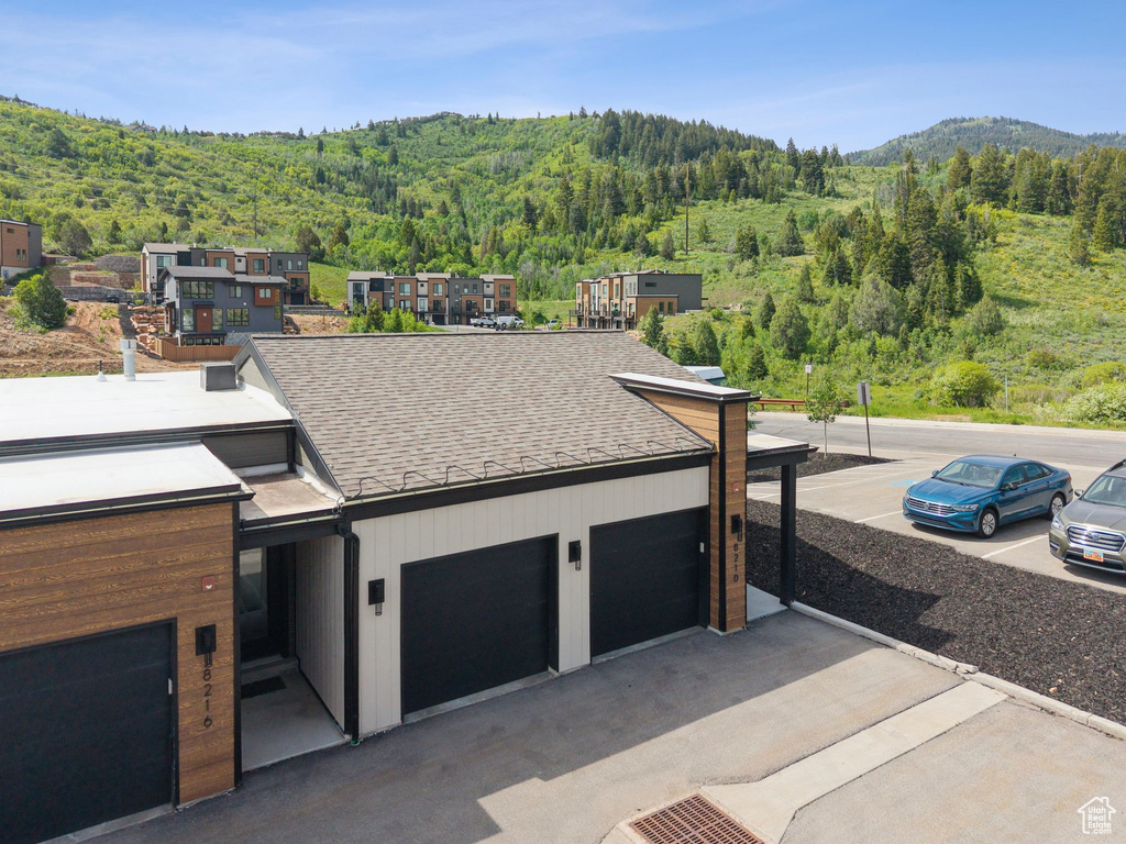 Modern home featuring a wooded view, a shingled roof, and a mountain view