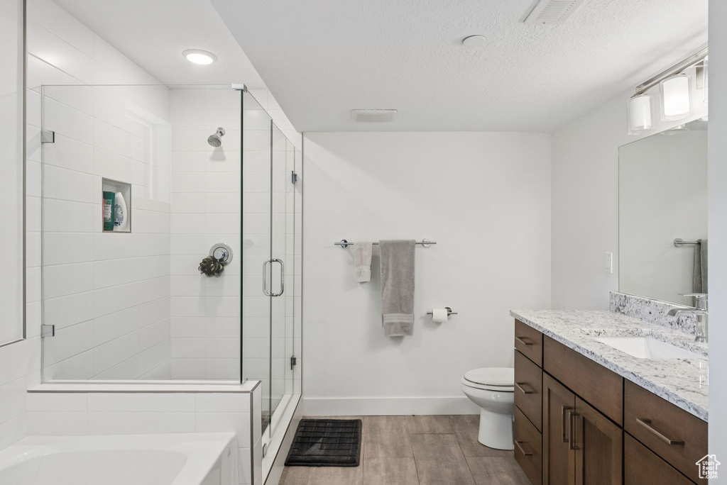 Bathroom with vanity, wood finished floors, a stall shower, toilet, and baseboards