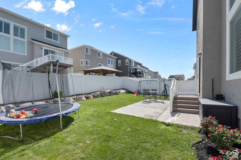 View of yard featuring a trampoline, a patio area, and a residential view