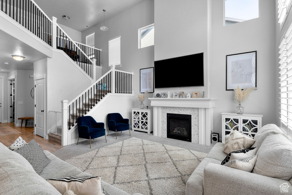 Living area featuring a high ceiling, healthy amount of natural light, stairway, and a fireplace