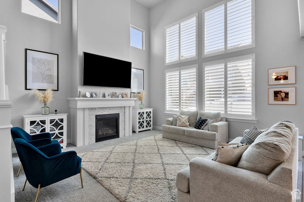 Living room with carpet floors, a high ceiling, and a glass covered fireplace